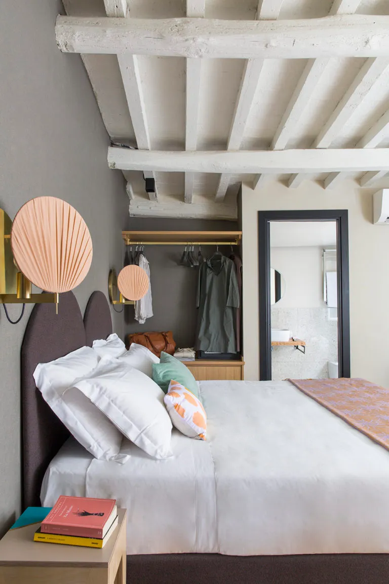 A minimalist bedroom with wood accents, white bedding, and modern decor.