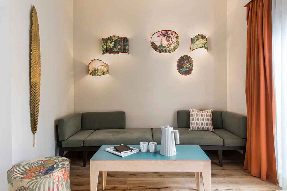 A modern living room with a green sofa, decorative wall plates, and a blue coffee table.