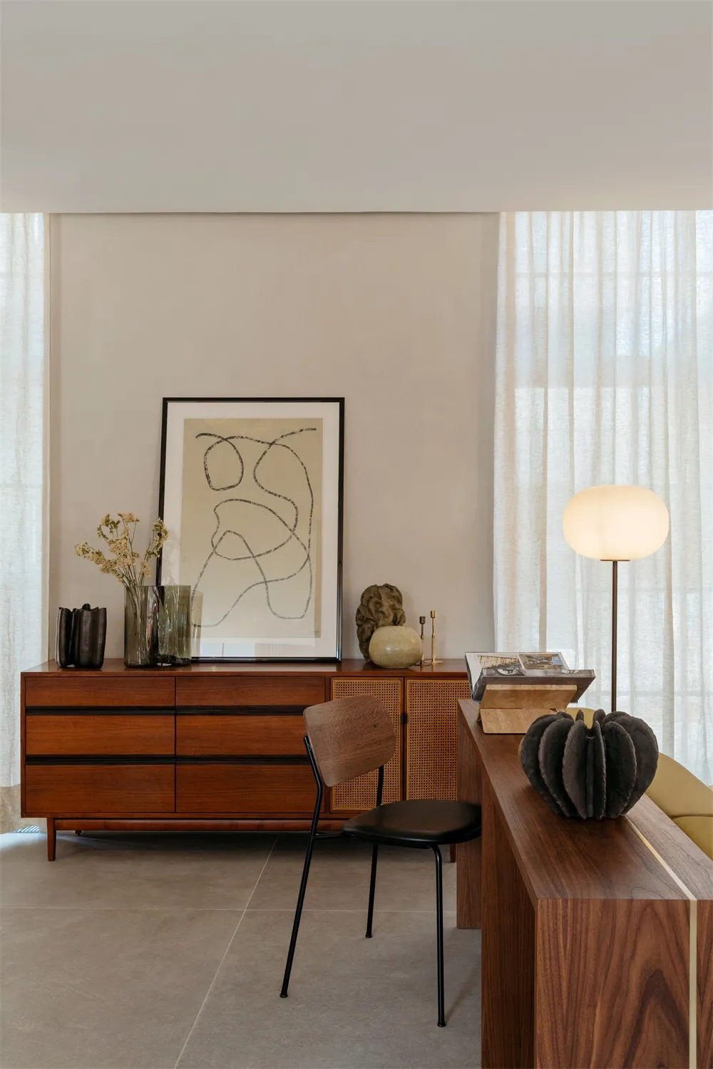 A minimalist living room featuring wooden furniture, a floor lamp, and modern decor elements.
