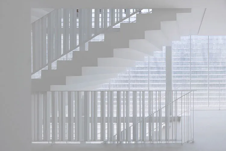 A modern floating staircase with glass railings and white steps and frame.
