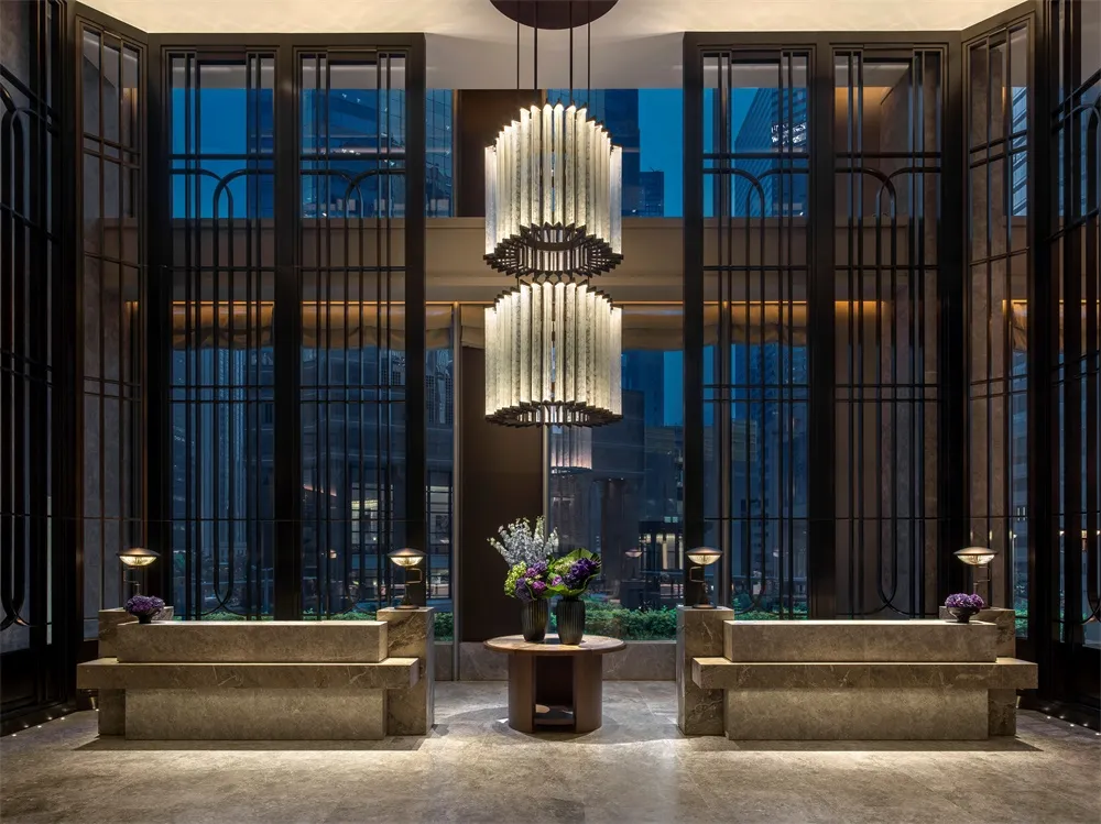 Modern hotel lobby with concrete walls, glass doors, and metal accents.