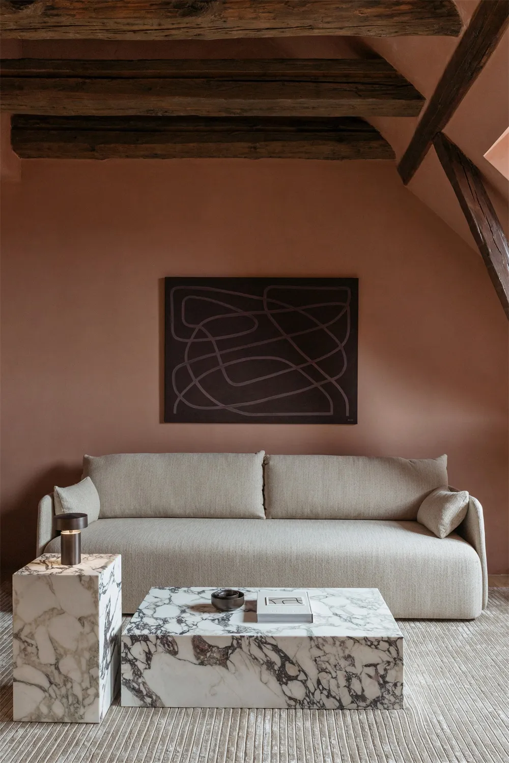 Modern minimalist living room featuring a beige sofa with marble accents and a marble coffee table.