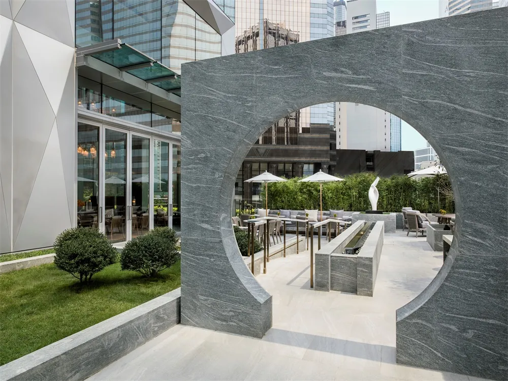 An outdoor patio made of granite with modern seating arrangements and greenery.
