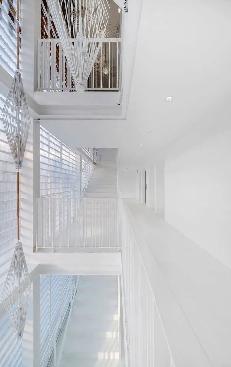 A minimalist white staircase with white railings in a modern architectural setting.