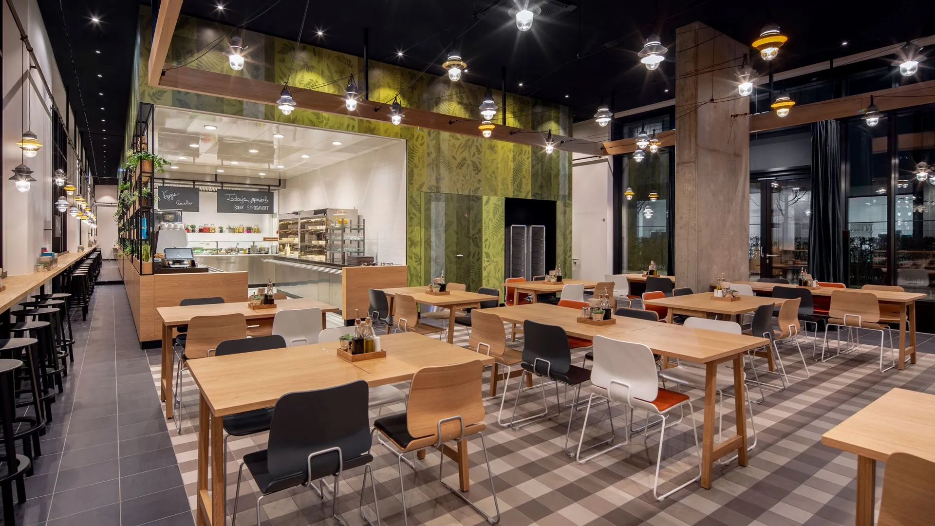 A modern, minimalist restaurant interior with wooden tables, concrete accents, and glass walls.