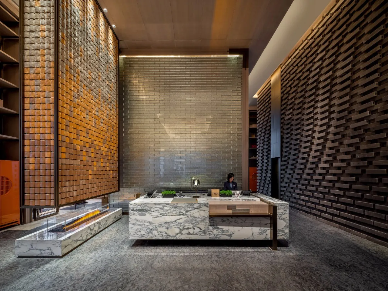 A modern hotel reception desk with marble and concrete finishes.