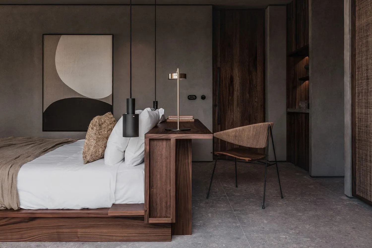 A modern minimalist bedroom featuring a bed with a wooden headboard, white bedding, and a wooden desk with a lamp.