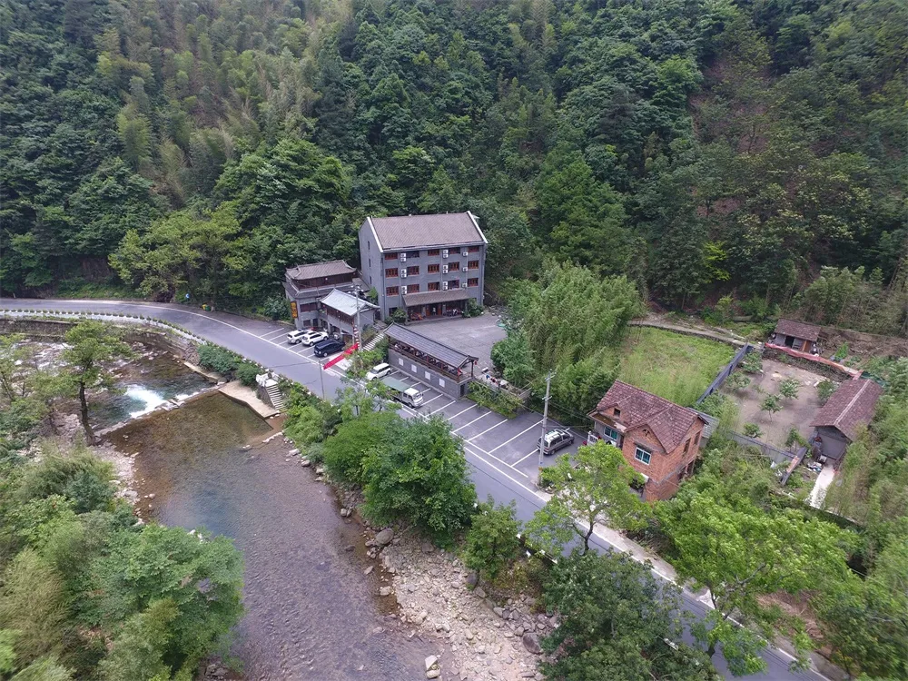 度假酒店的俯瞰視角,周圍環繞茂密綠意,磚塊與混凝土建築搭配木質元素。