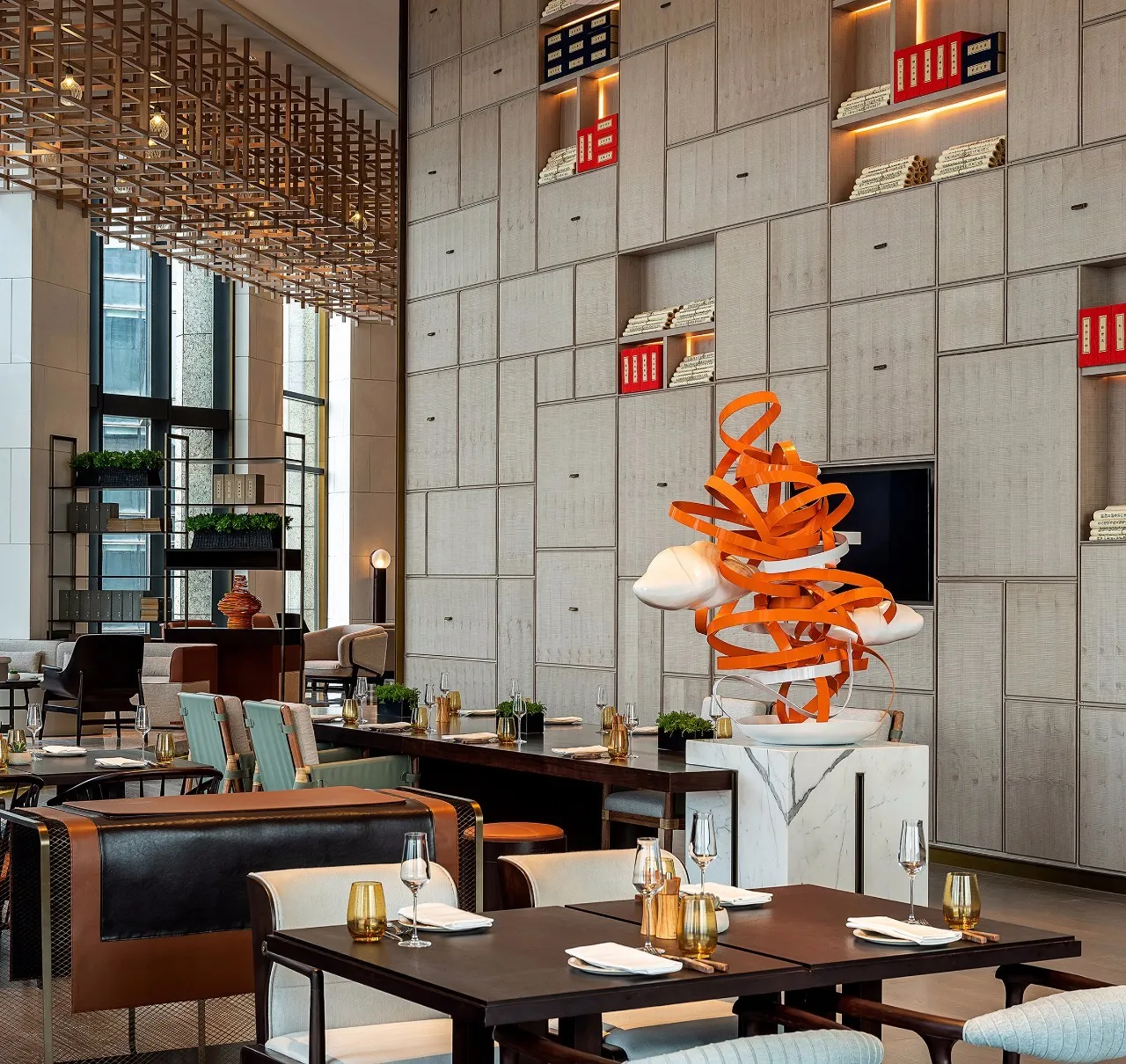A modern restaurant with metal and leather seating, marble countertops, and a glass art installation.