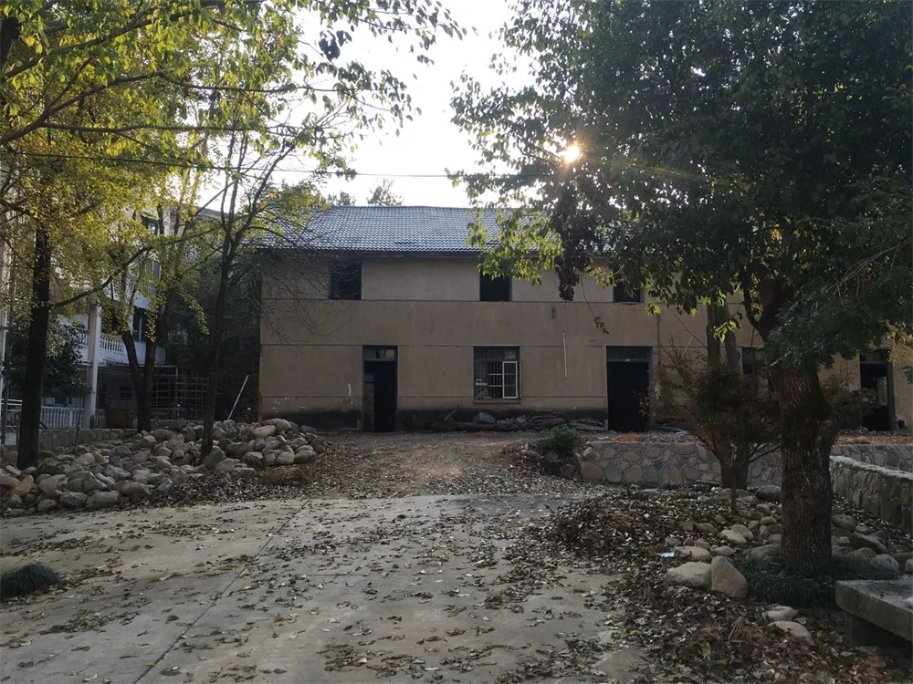 Concrete residential building with trees and a courtyard.