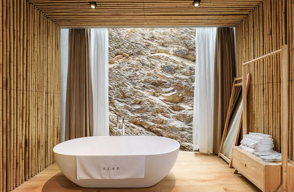 A minimalist bathroom featuring stonework materials and a window with a scenic view of a rocky landscape.