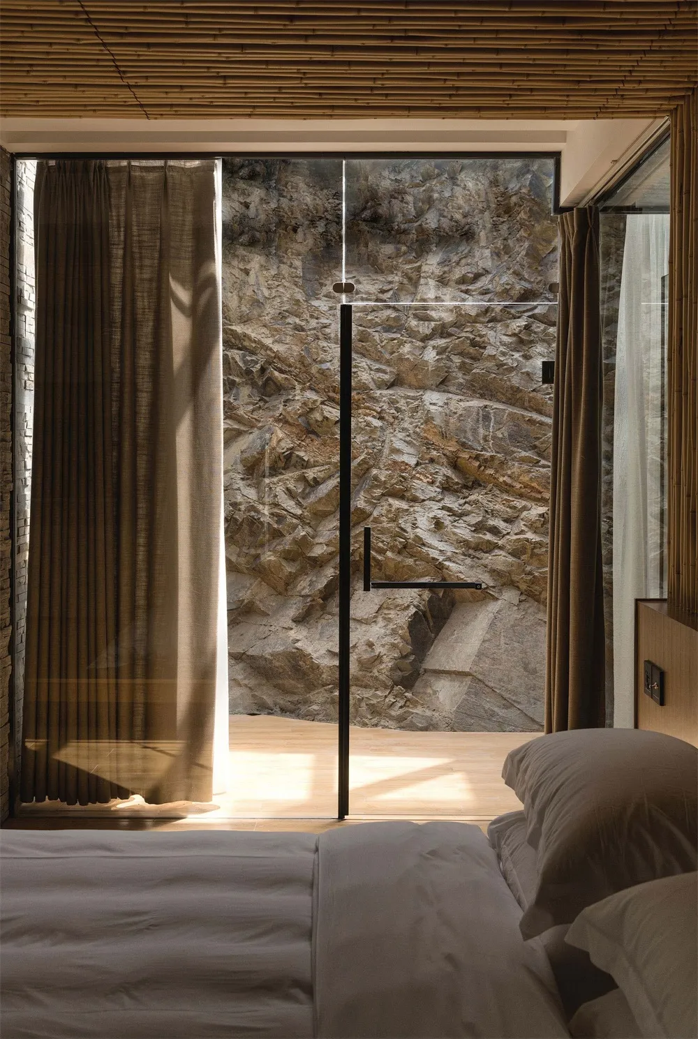 A minimalist bedroom with wood flooring and stone walls