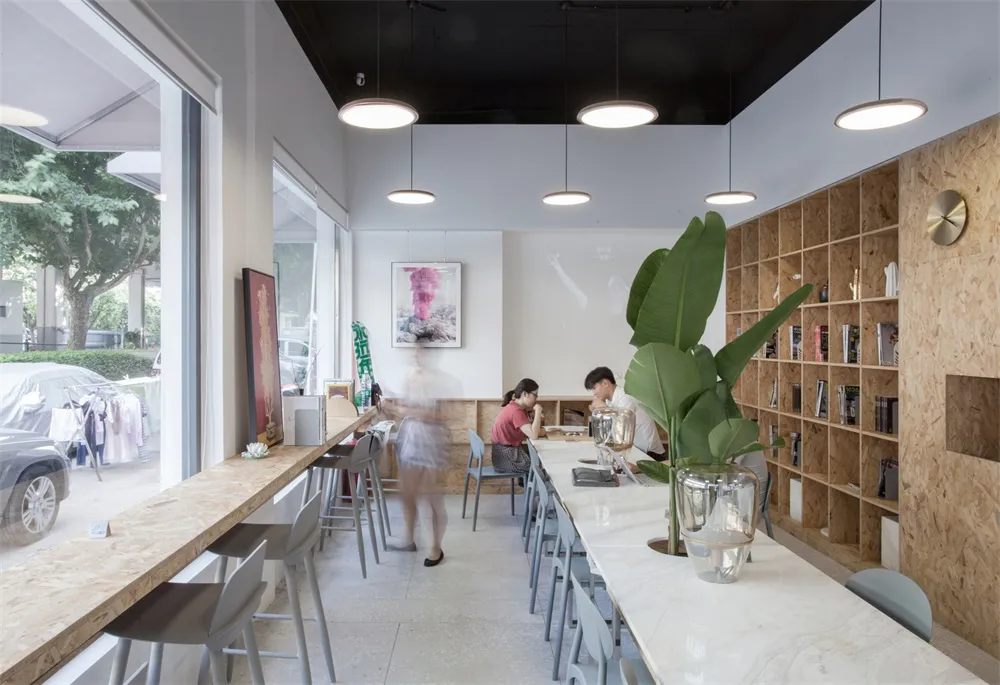 A modern cafe interior with a marble bar, wooden shelves, and metal stools.