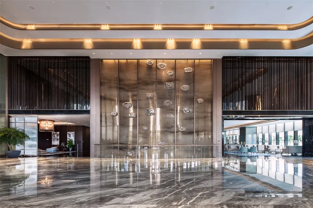 Modern interior design of a hotel lobby featuring glass walls and marble floor.