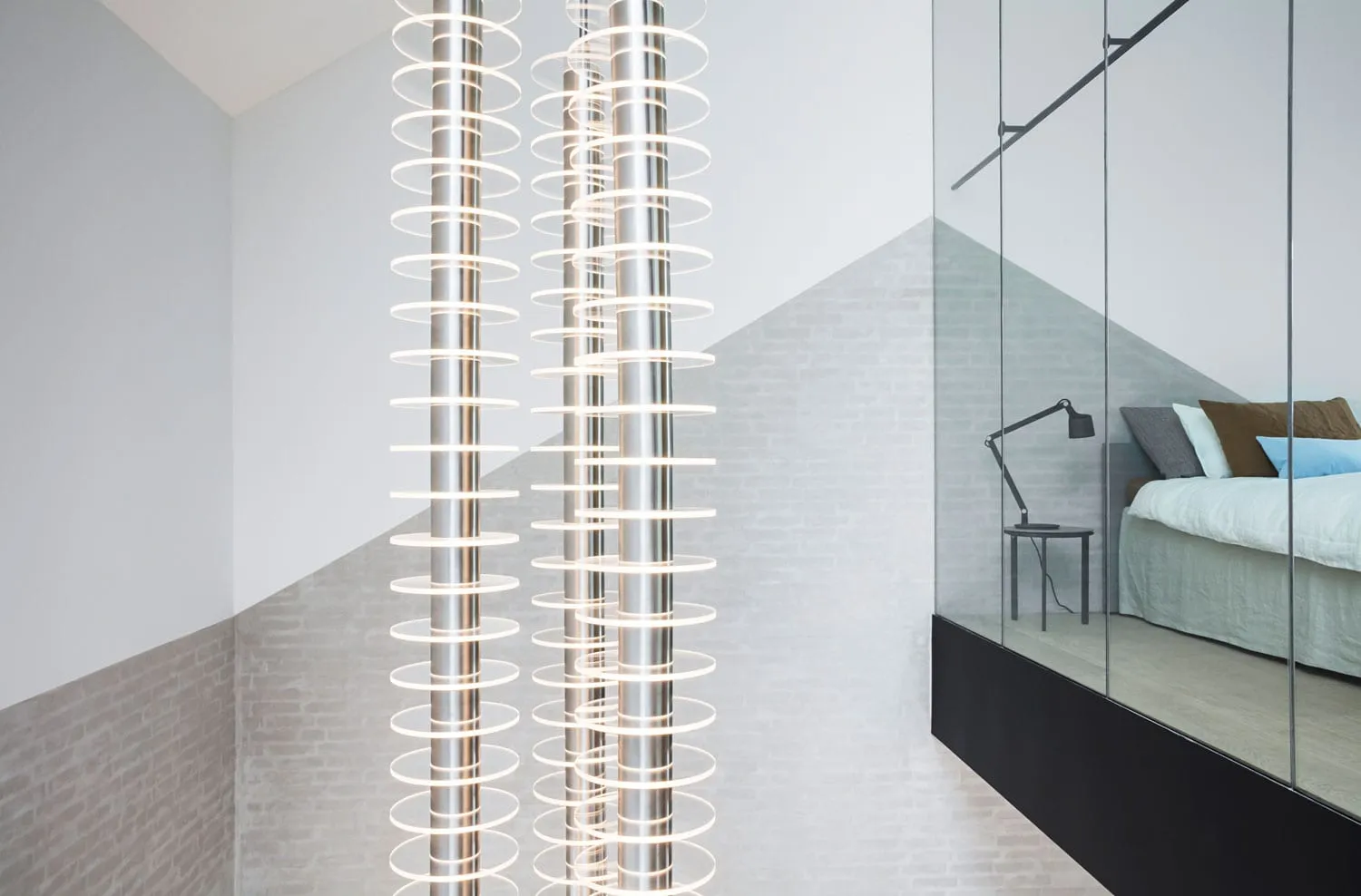 A modern minimalist bedroom with metallic pendant lights and a glass partition.