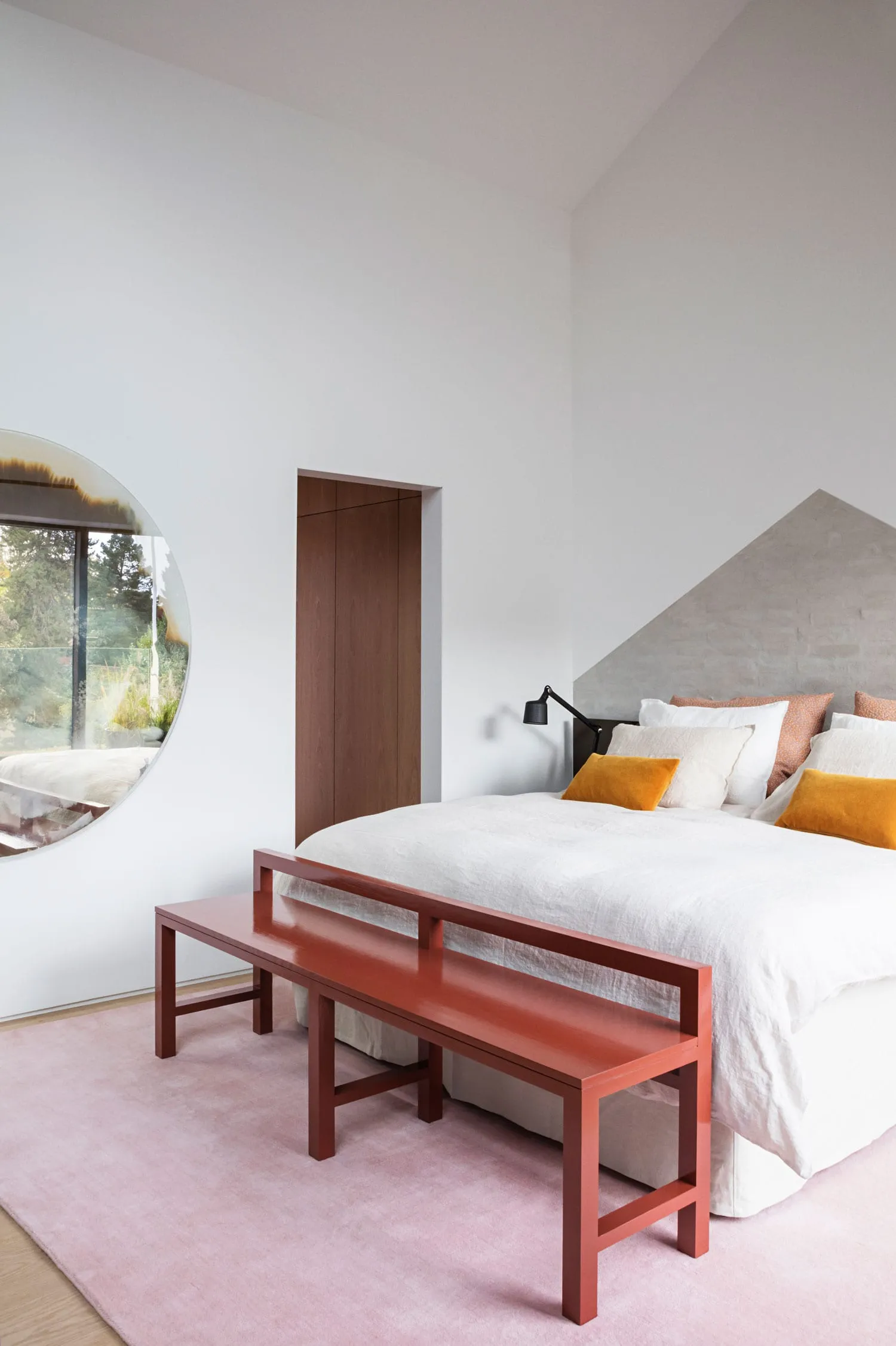 A modern minimalist bedroom featuring a concrete bench and a bed with yellow accent pillows.