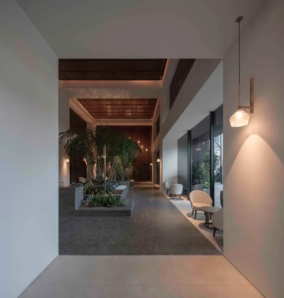 A modern office lobby featuring concrete, glass, and wooden materials.