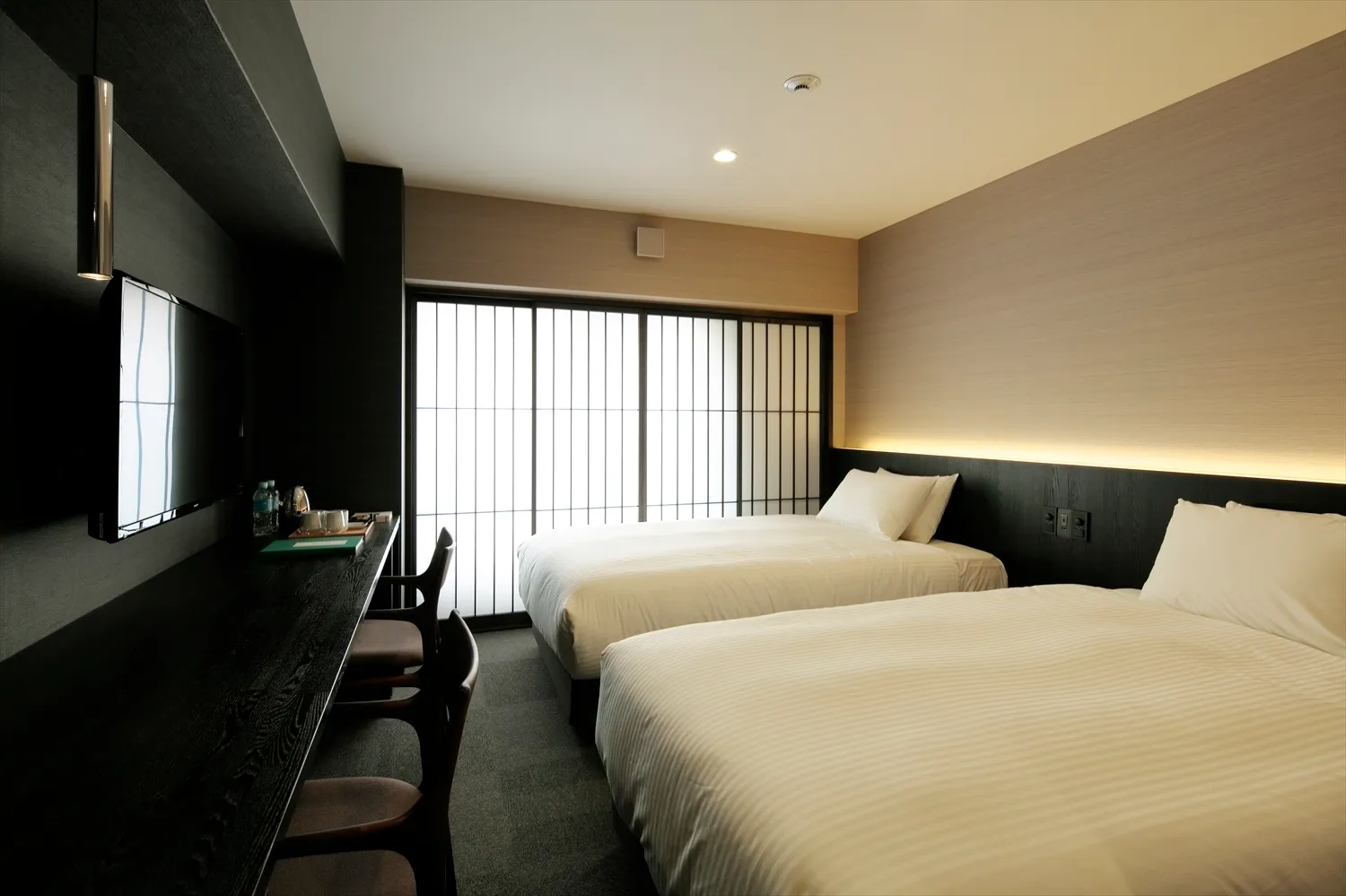 Modern minimalist hotel room with a textured fabric bedspread and a television mounted on the wall.