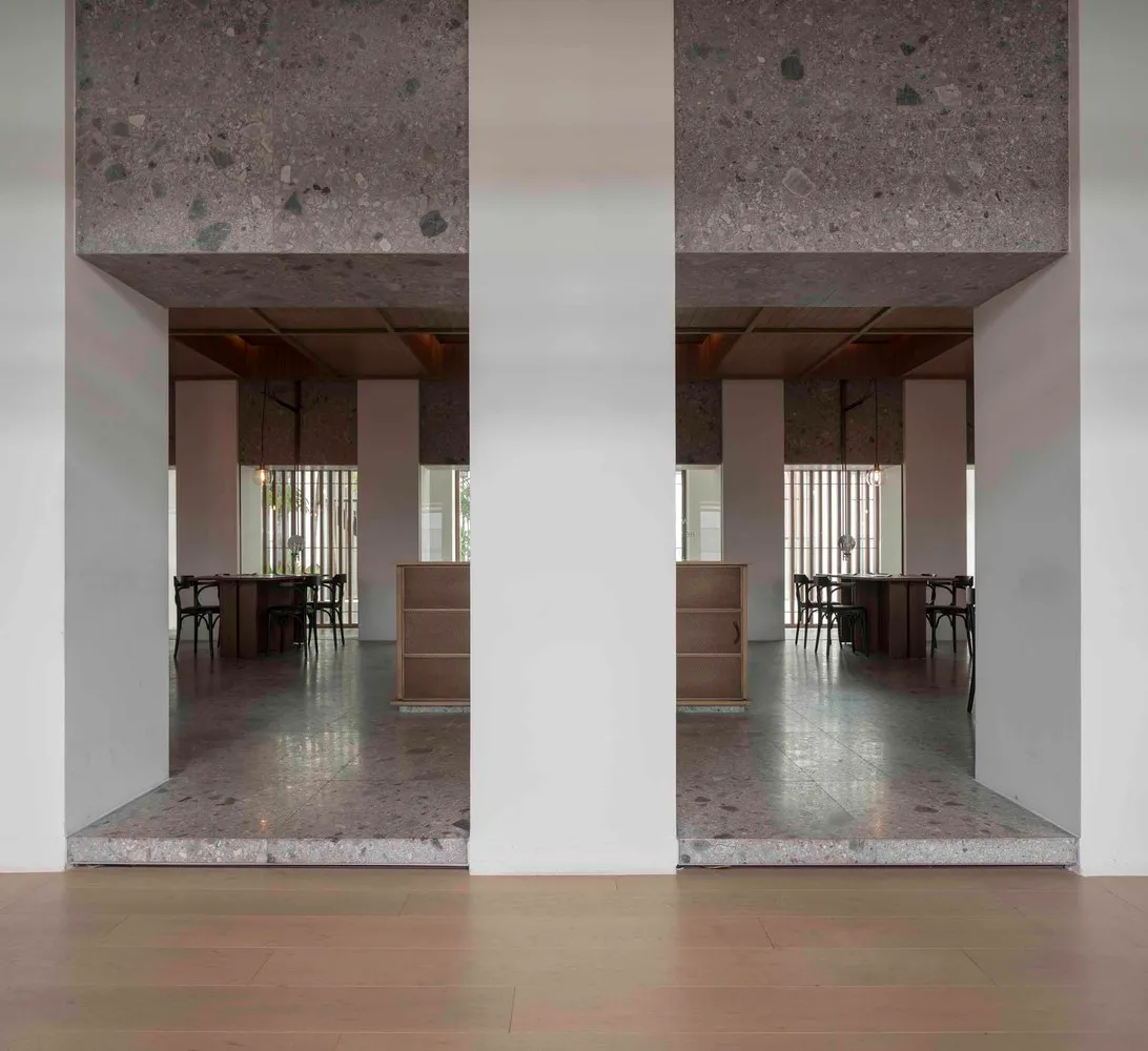 Modern restaurant interior with concrete floors and walls, featuring tables and chairs.