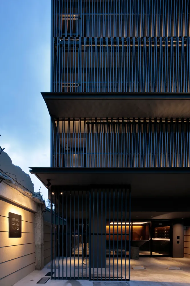 Modern exterior of a hotel building with metallic cladding on a concrete facade at dusk.