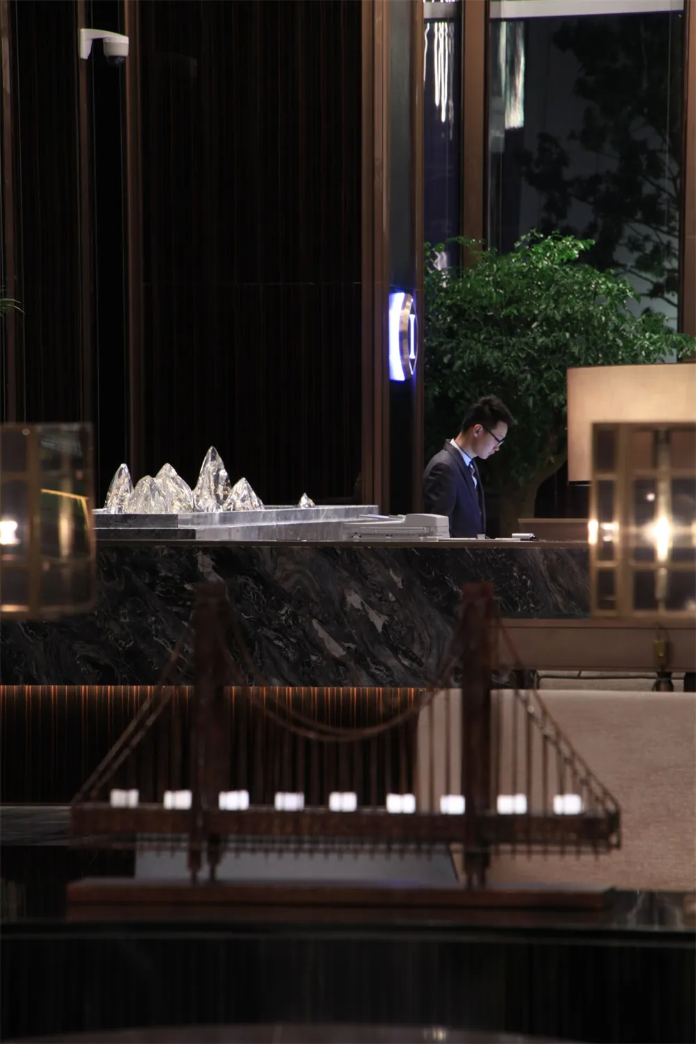 現代酒店接待櫃檯，搭配大理石檯面與玻璃雕塑。