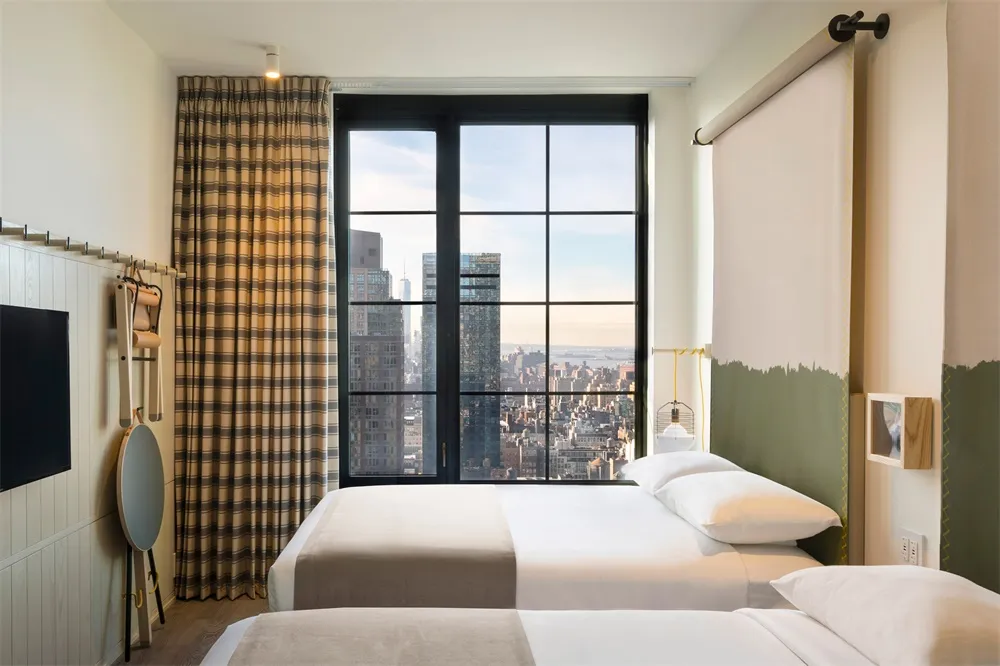 A modern hotel room featuring a city view, textiles, and a large window.
