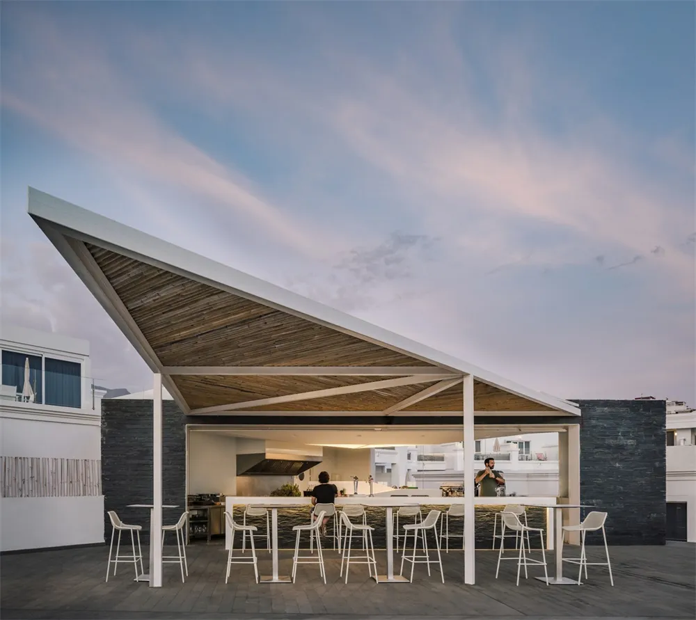 Rooftop bar with wooden roof structure, metal frames, and high seating.