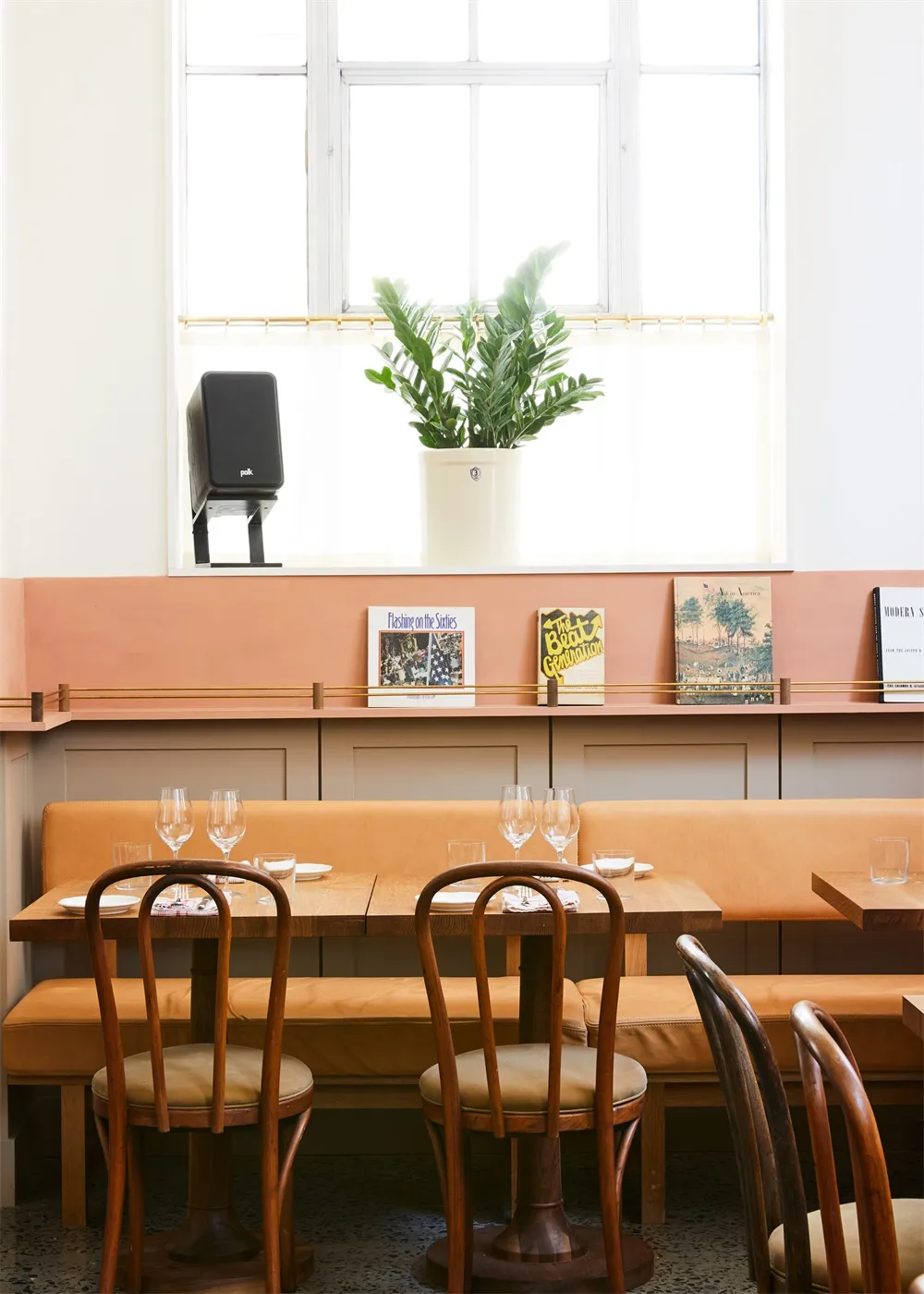 Interior design of a cafe featuring mid-century modern furniture with wooden tables and chairs, brown leather seating, and de