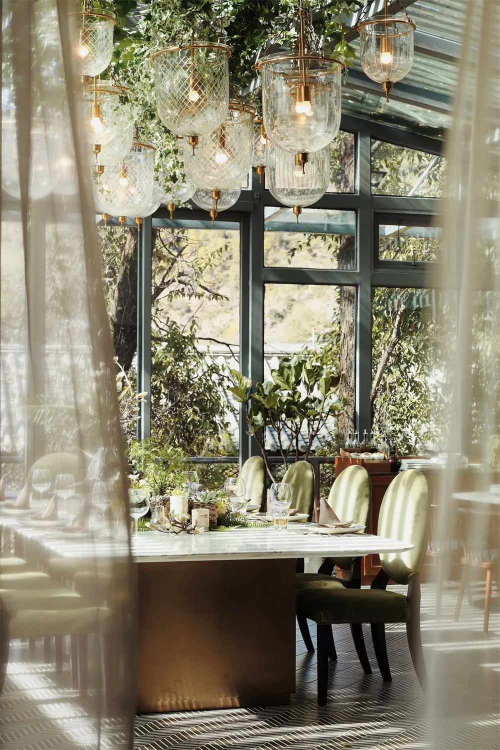 Modern commercial restaurant with glass walls, metal chairs, and green foliage.