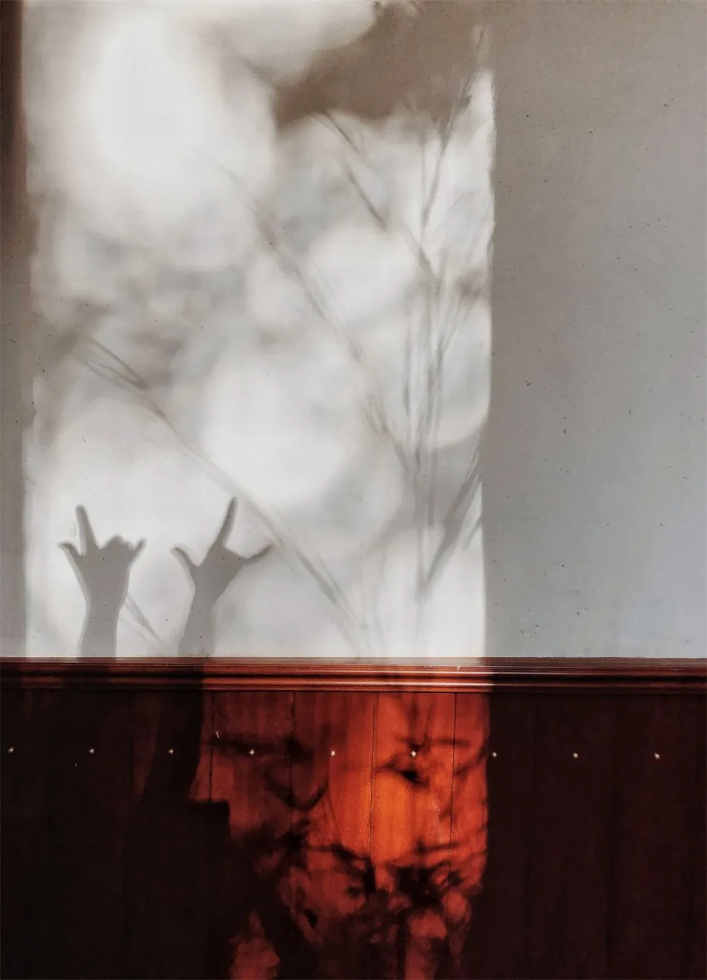 A shadow art installation featuring hands striking an 'I love you' gesture cast on a textured wall.