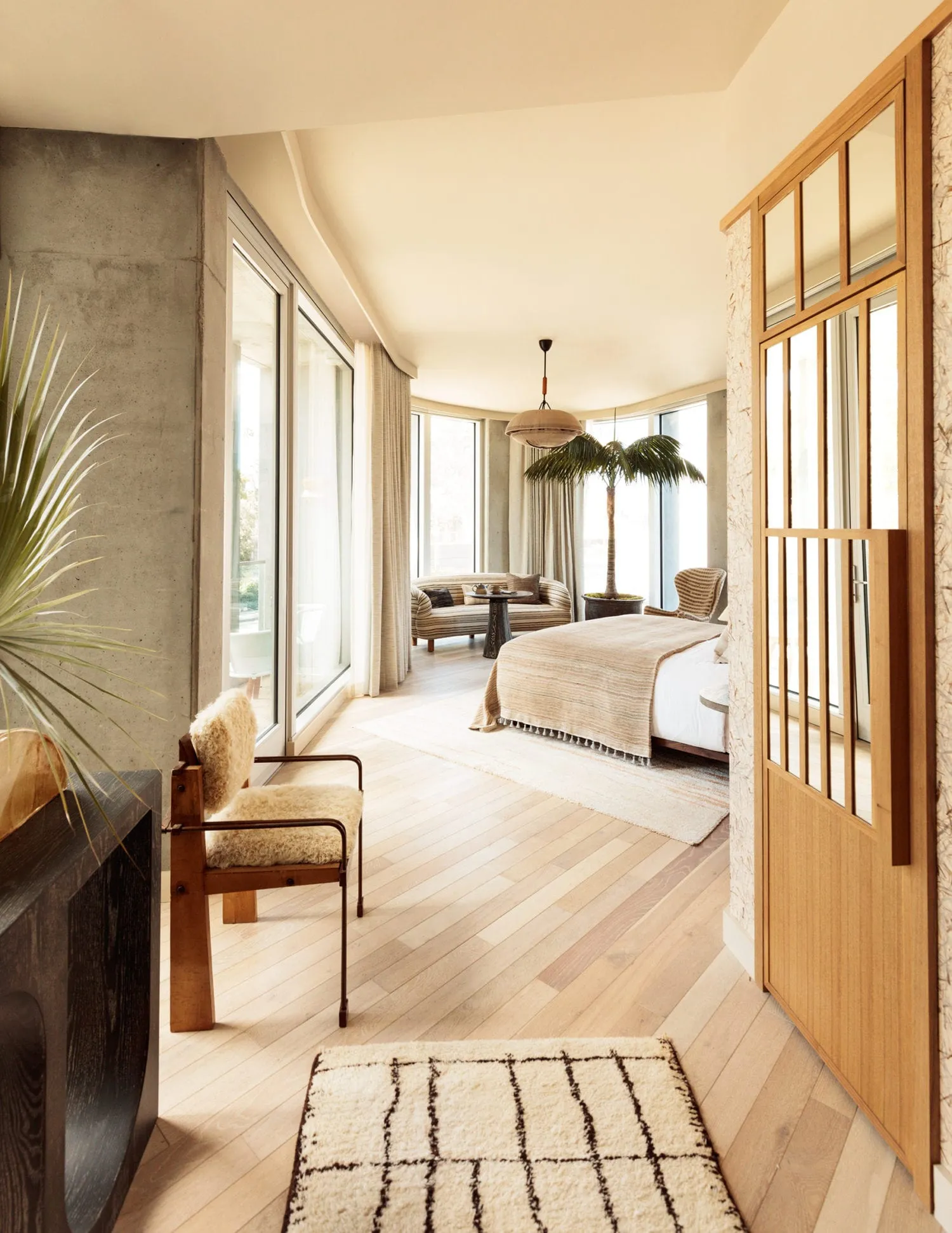 A modern minimalist bedroom featuring a white bed with a wood frame and white walls, complemented by a wooden floor with a bl
