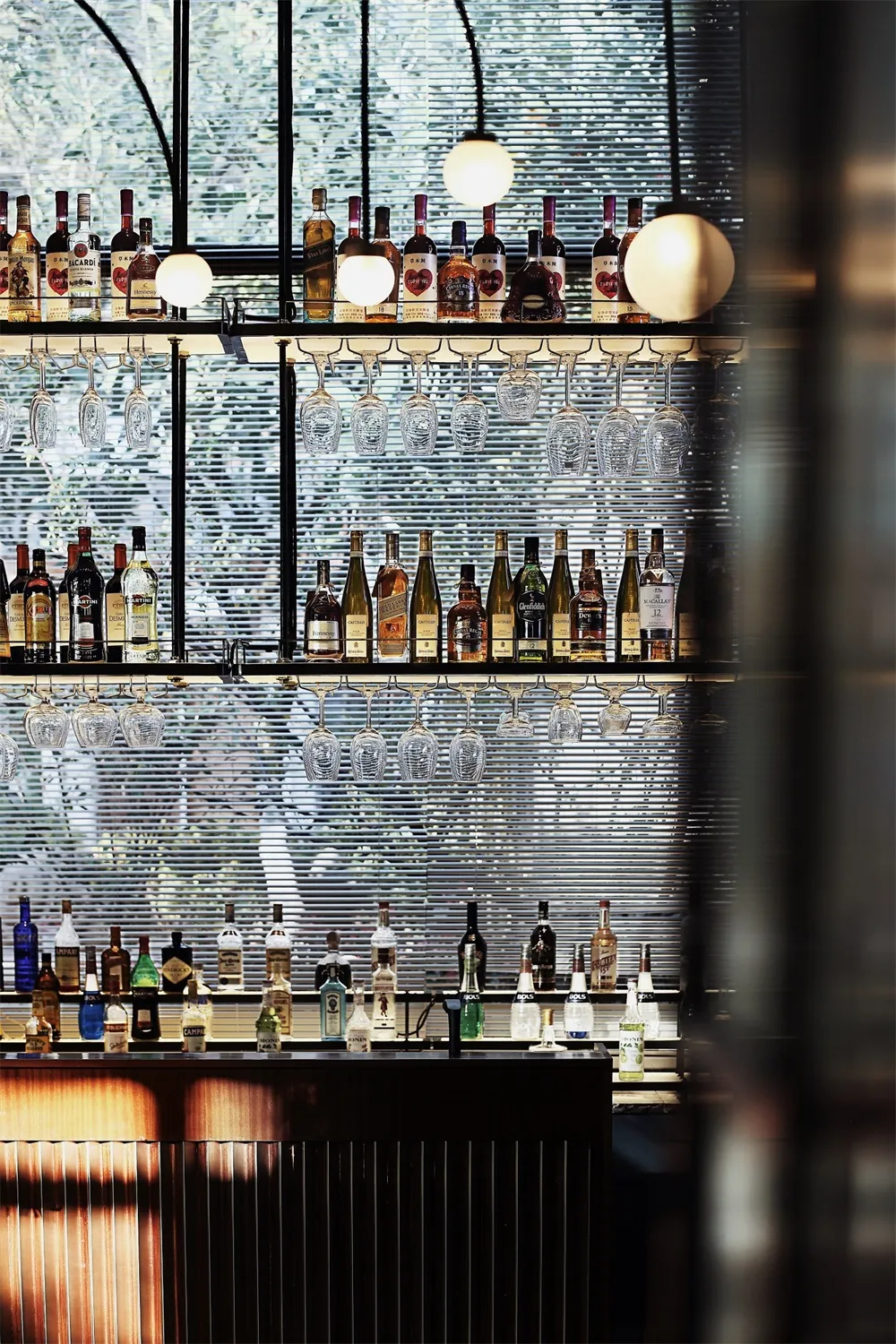 現代酒吧室內展示各式酒瓶與懸掛的玻璃杯。