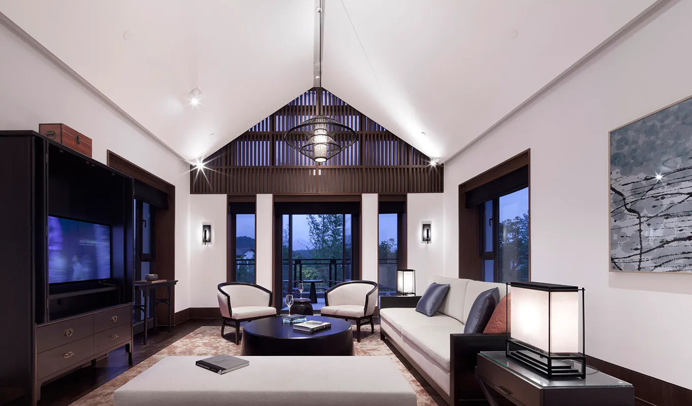 Modern living room with white furniture, wooden accents, and large windows.