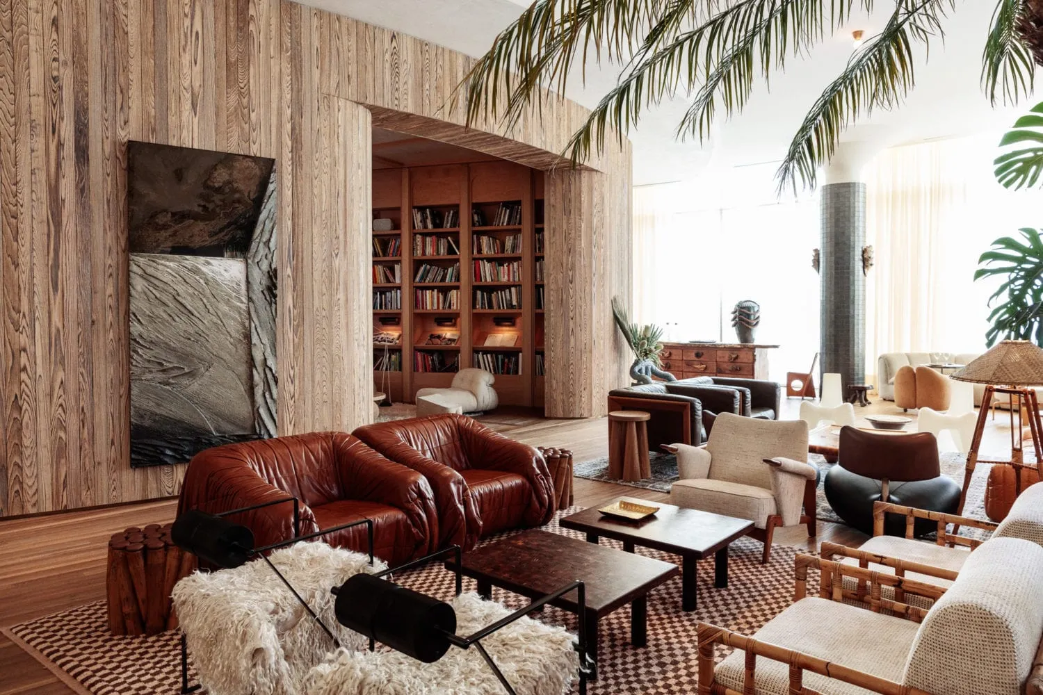 A modern living room featuring leather sofas, wooden walls, and upholstered chairs.