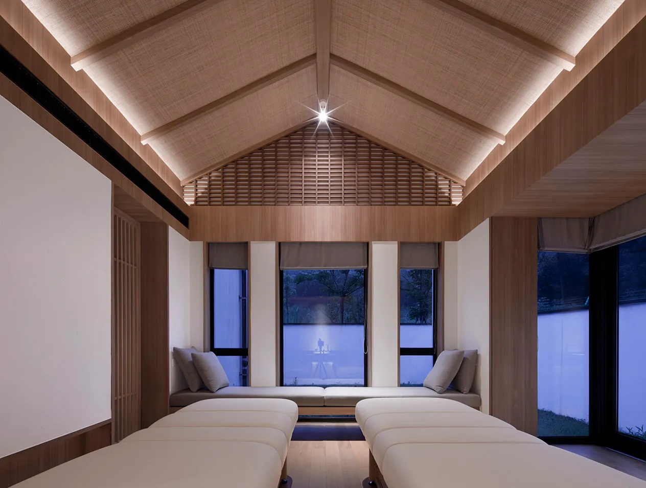 Spa room with two white beds and a high wooden ceiling.