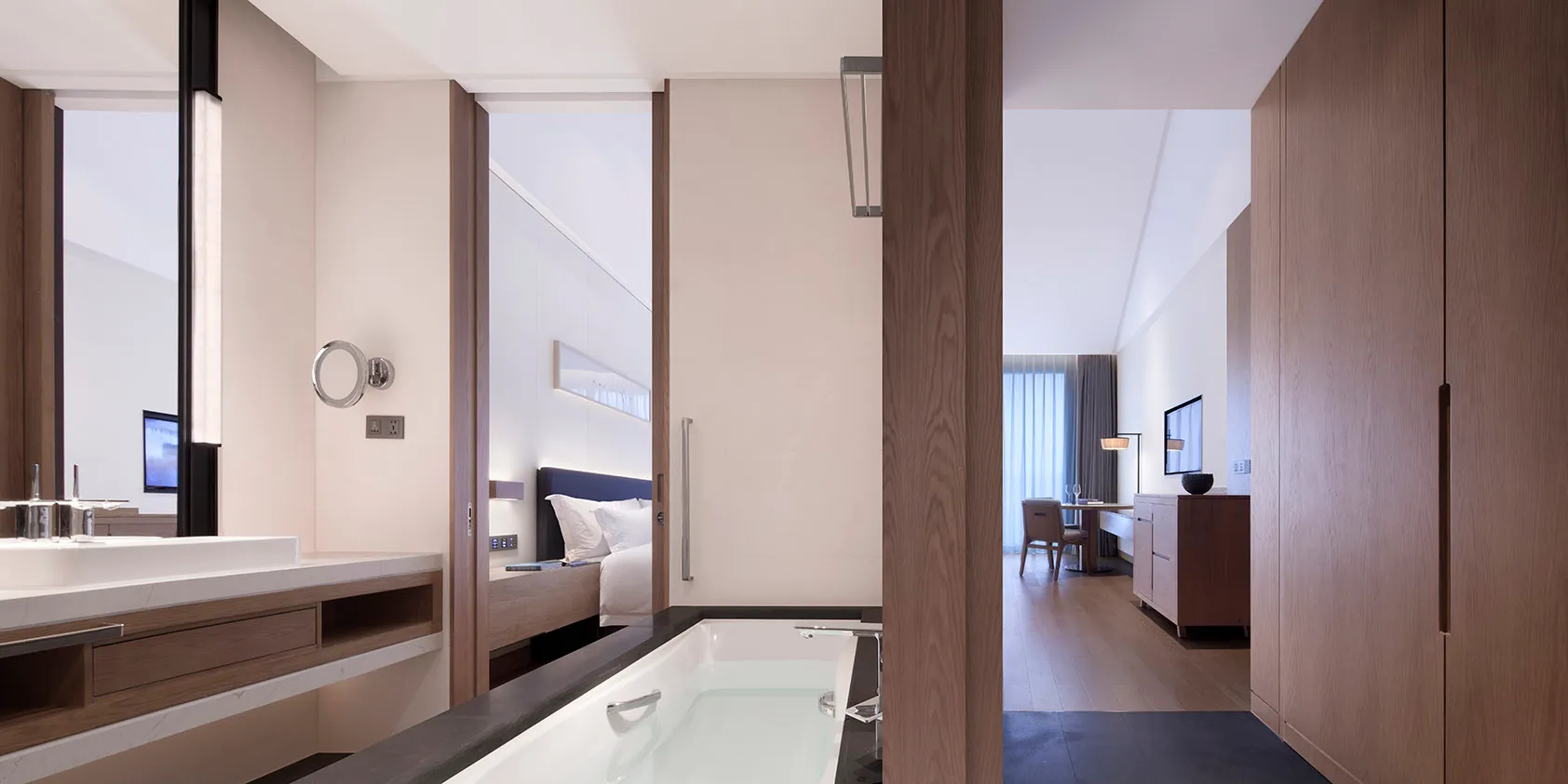 Modern residential bathroom featuring wood finishes and marble accents, with a view into the adjacent room.