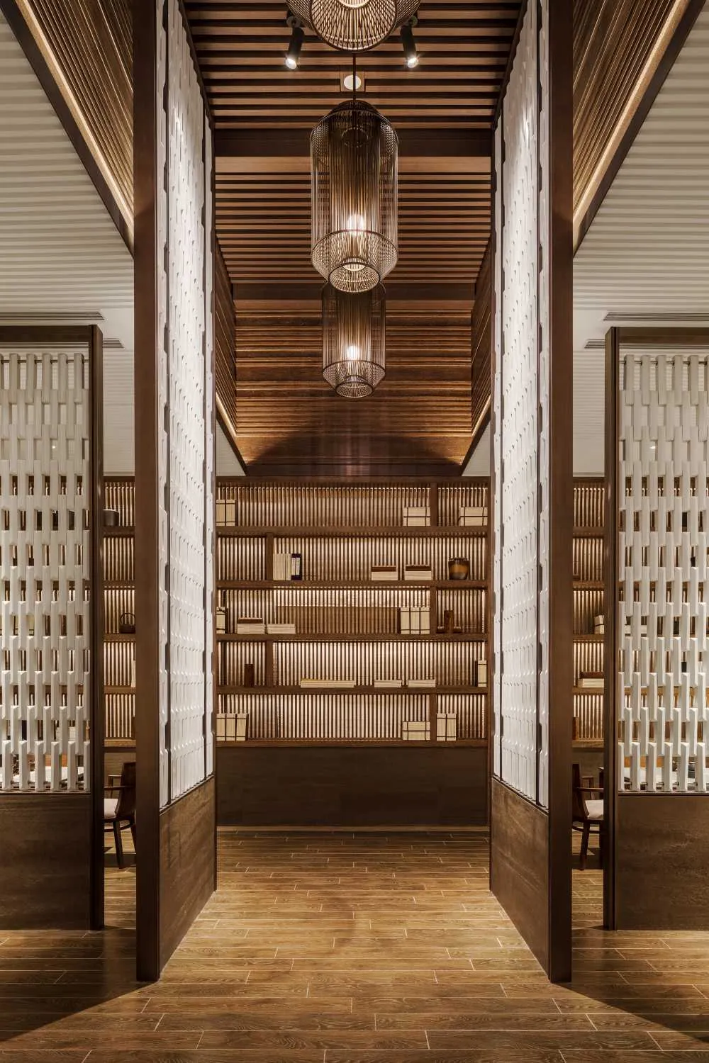 A modern wooden library with shelves filled with books and wooden light fixtures hanging from the ceiling.
