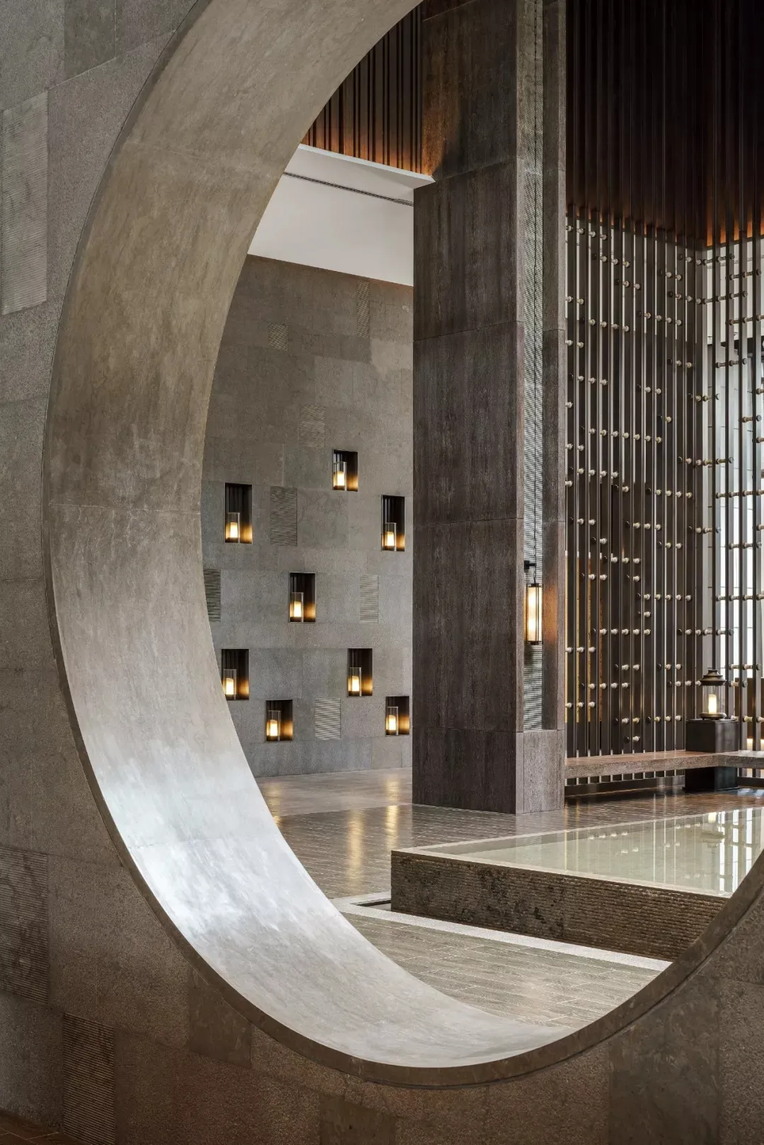 Modern hotel lobby featuring concrete walls and floors with warm lighting.