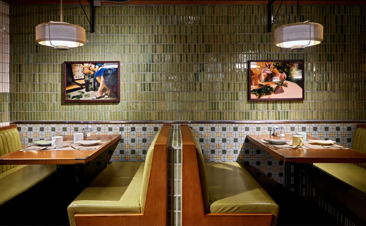 Restaurant interior with green tile walls and wooden tables with white tablecloths