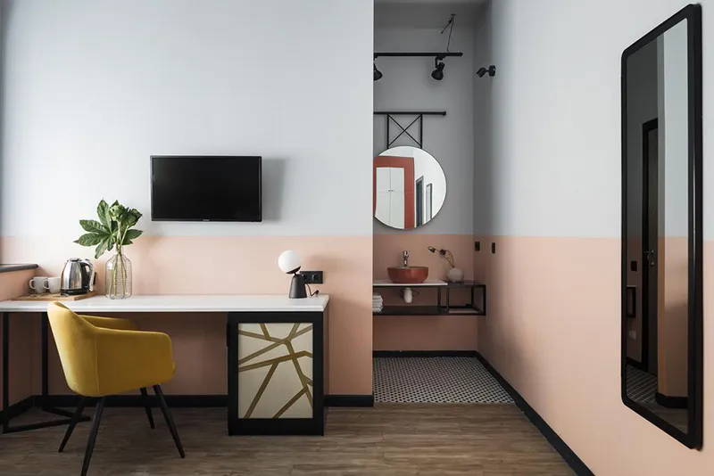 A modern, minimalist workstation featuring a sleek desk, a yellow chair, and a flat-screen TV.