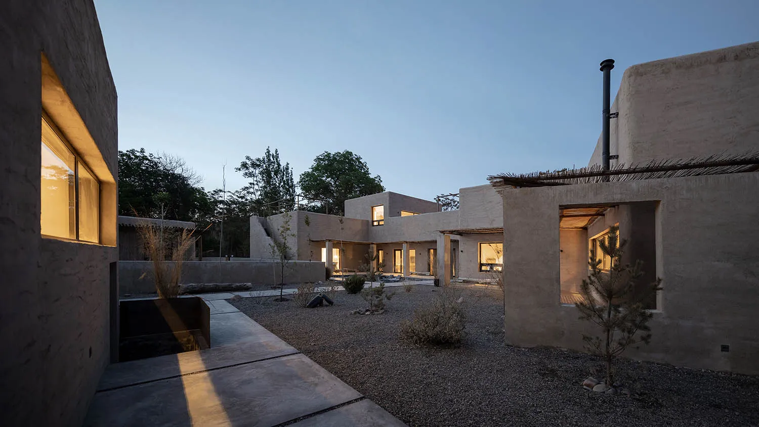 Modern residential exterior with adobe walls and white stucco accents.
