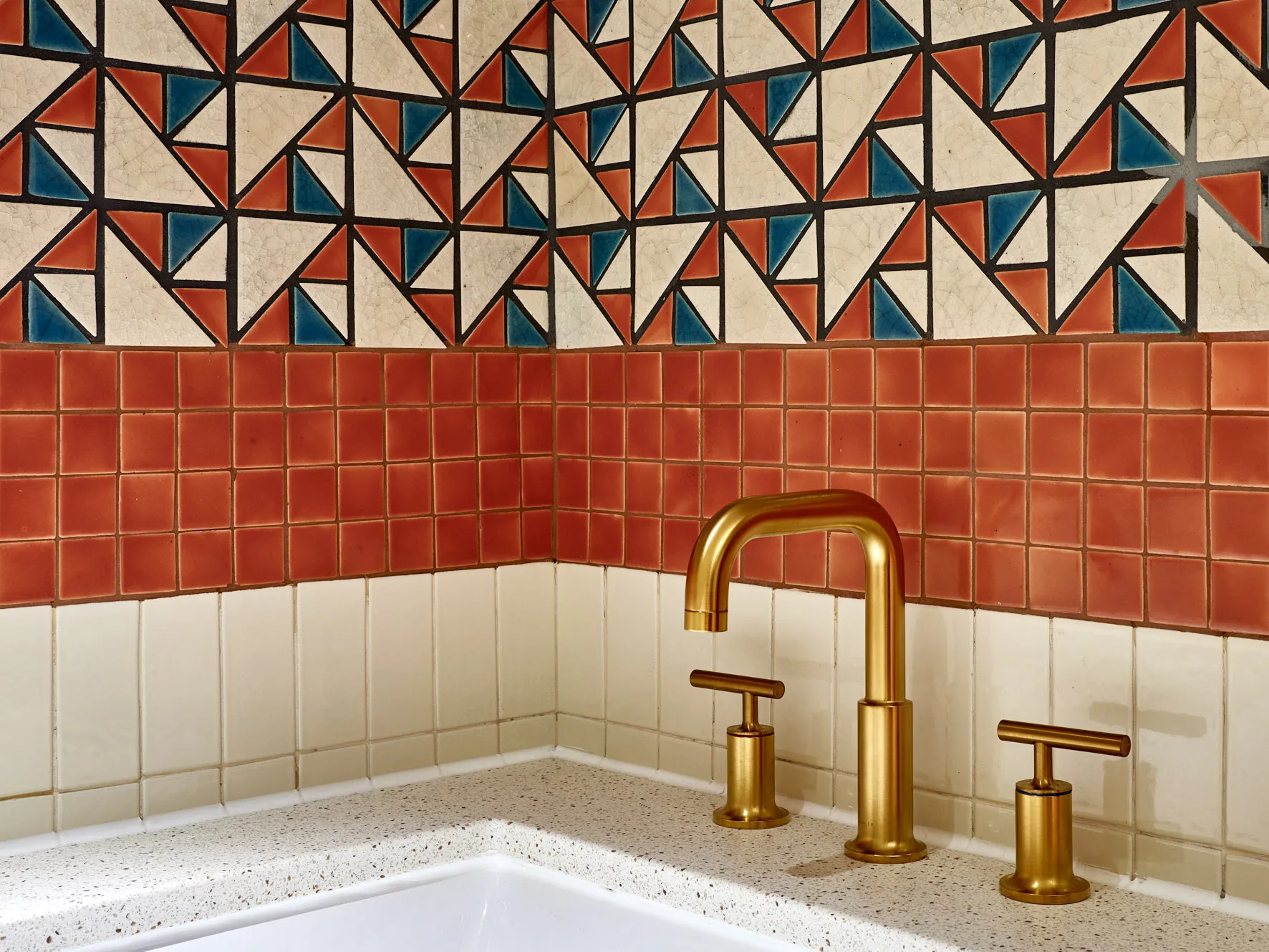 A modern kitchen with terrazzo tiles on the backsplash and a white countertop.