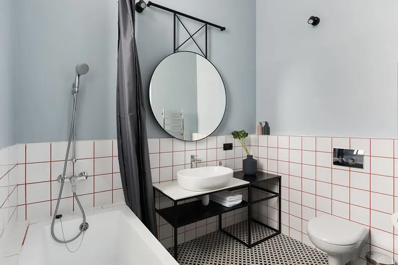 Modern minimalist bathroom featuring white and black tiled floor, white bathtub, and white sink with black faucet.
