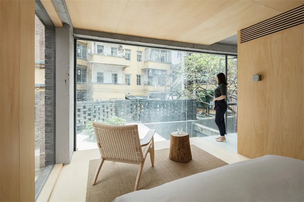 A minimalist bedroom featuring a large window with a view of the surroundings.