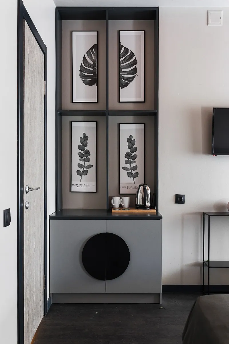 A minimalist residential coffee station with a metal shelf, black and white botanical prints, and a metallic kettle.