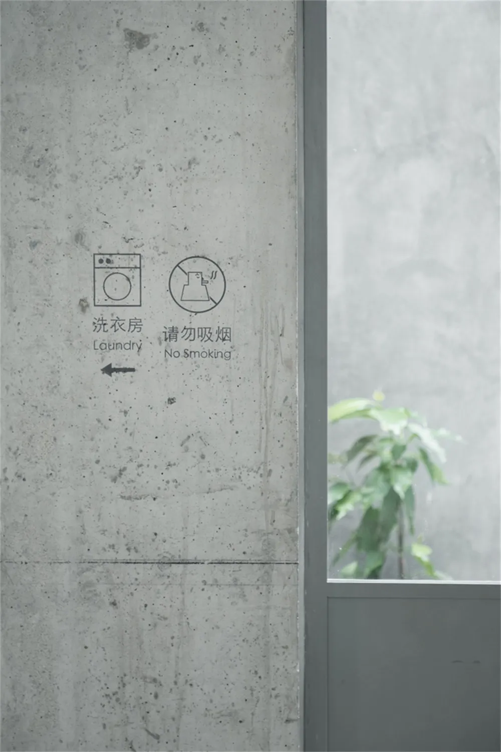 A minimalist concrete wall with signs for laundry and no smoking.