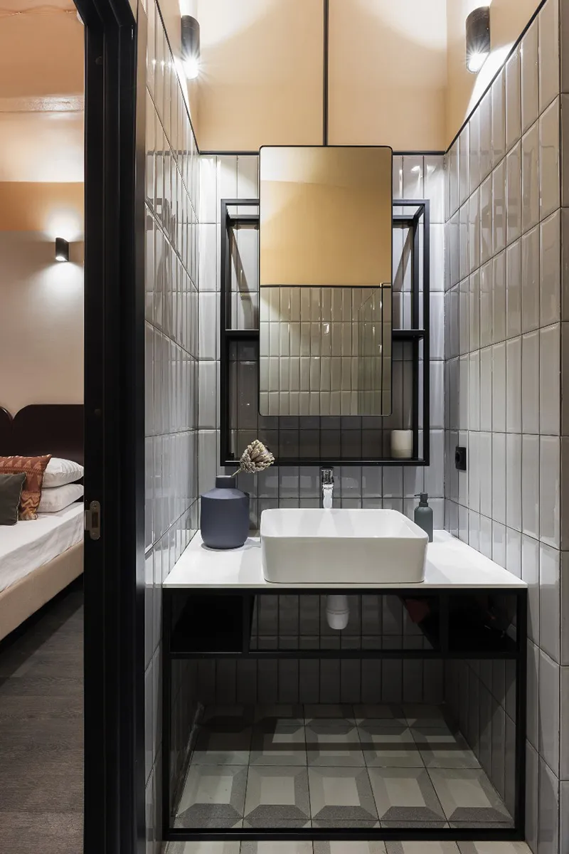 A modern bathroom with white ceramic tiles and a sink in front of a mirror.