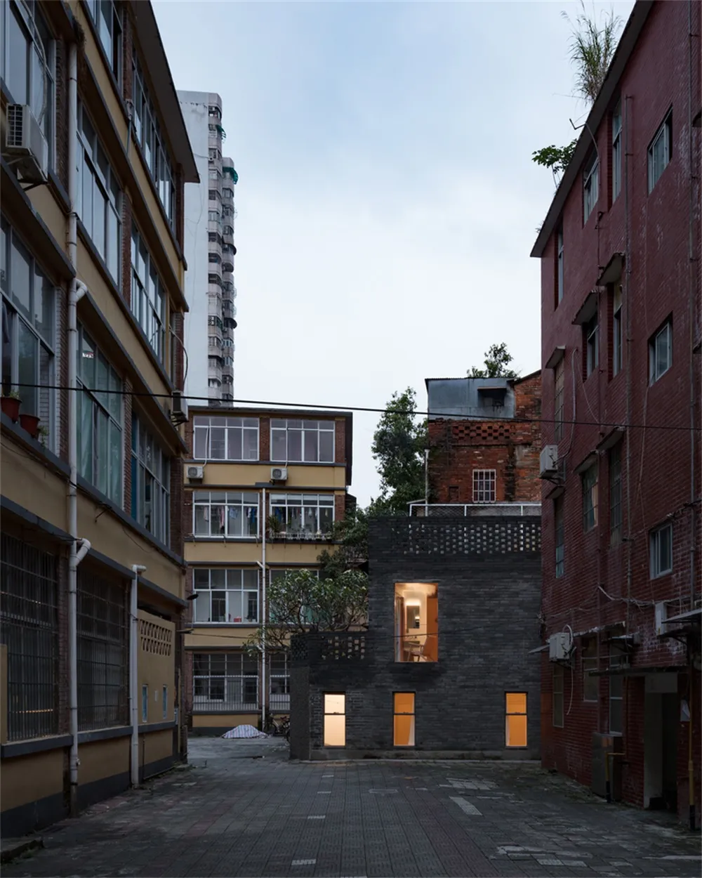 Modern black brick building in an urban setting with lights on.