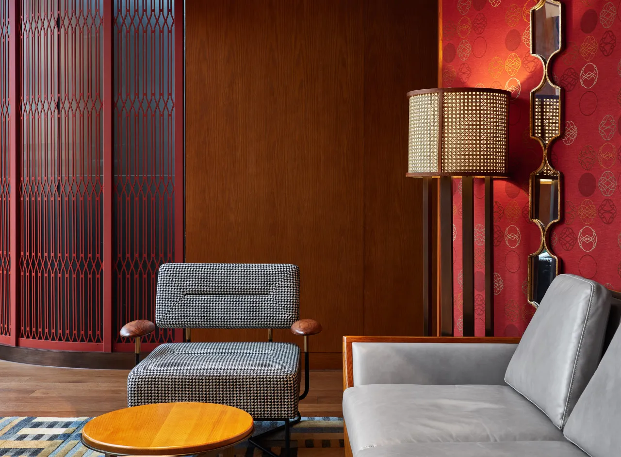 A modern living room featuring a gray sofa, a woven floor lamp, and a round wooden coffee table on a patterned rug.