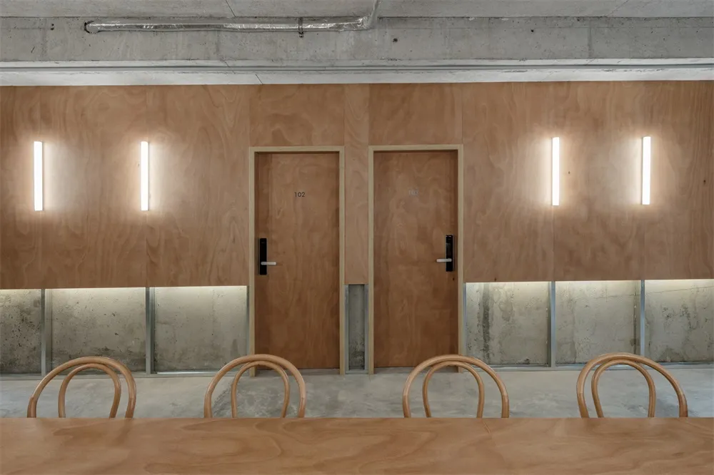 An office space featuring minimalist wooden paneling walls and tables.
